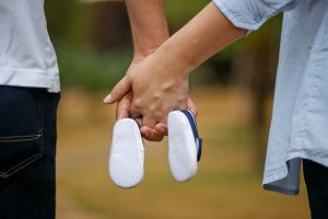 Padres dandose la mano y sujetando las zapatillas del bebe